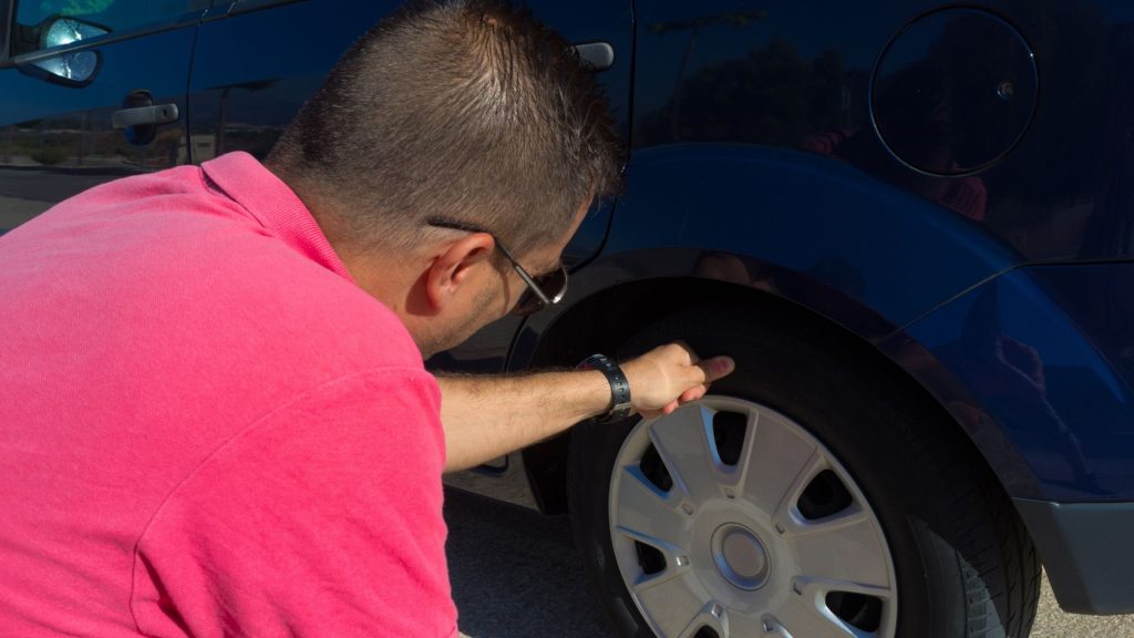 a man checking its vehicle's tire