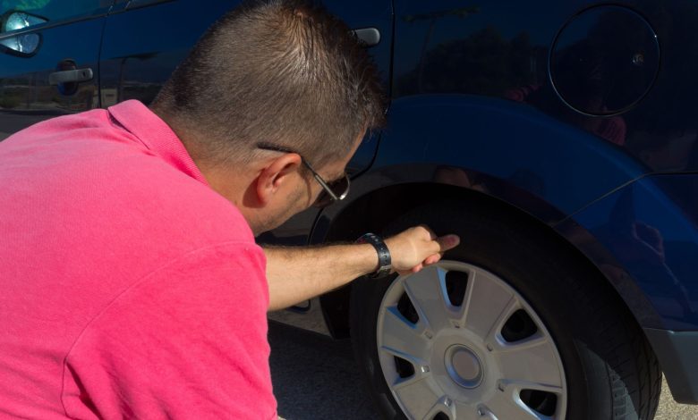 a man checking its vehicle's tire